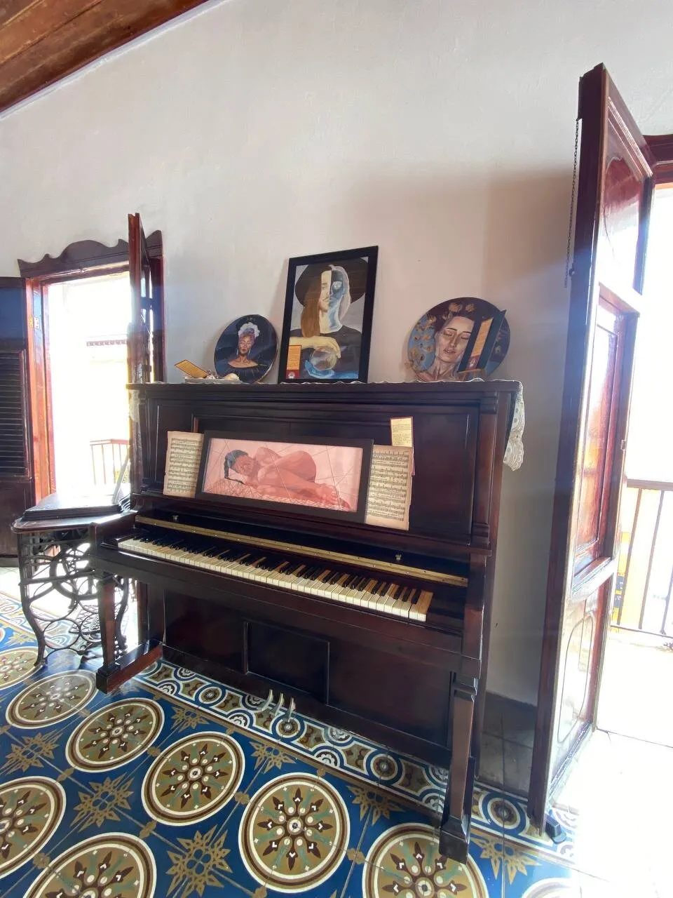 Piano de época rodeado de pinturas