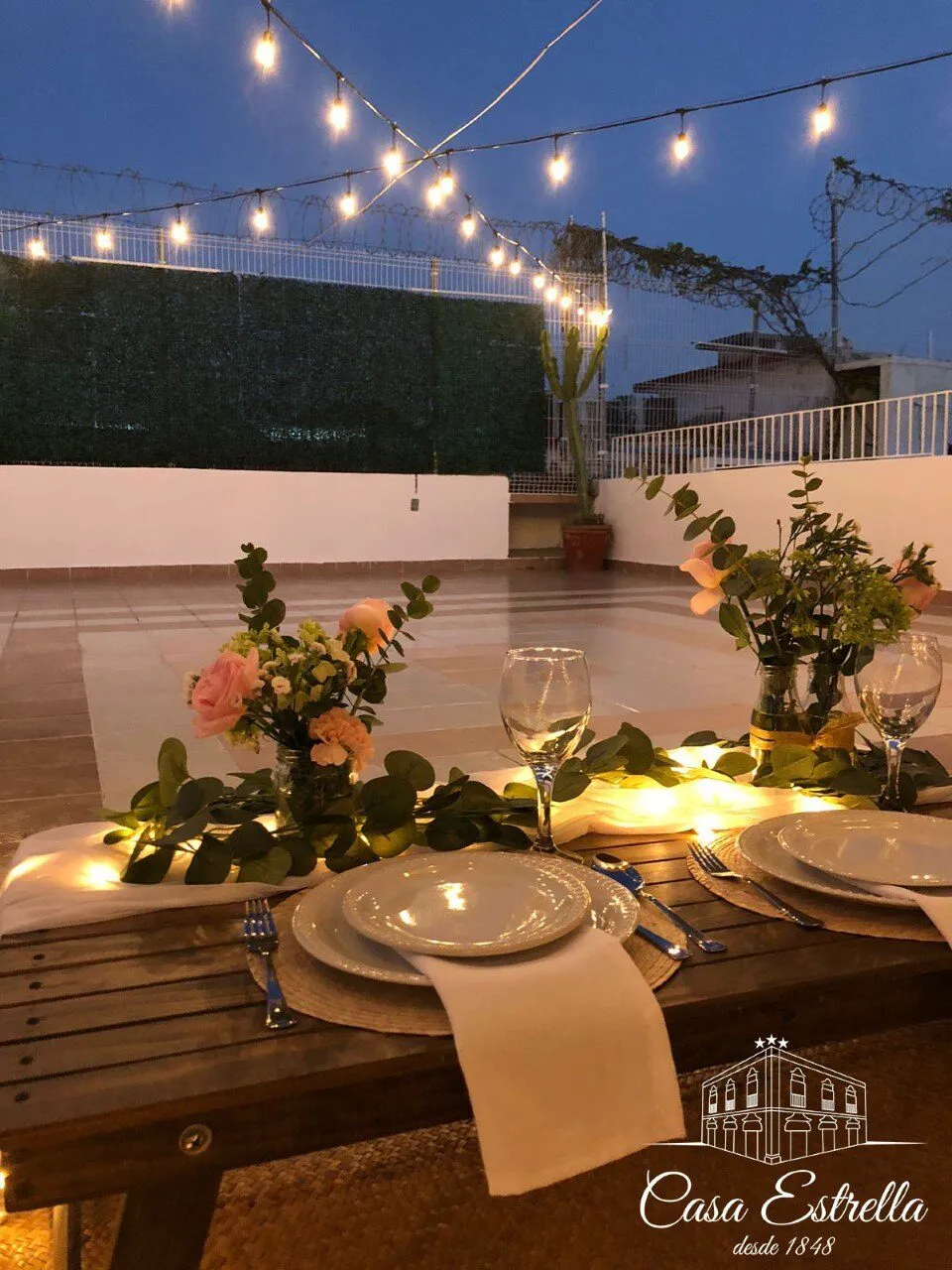 Mesa puesta con flores y velas en la terraza de noche